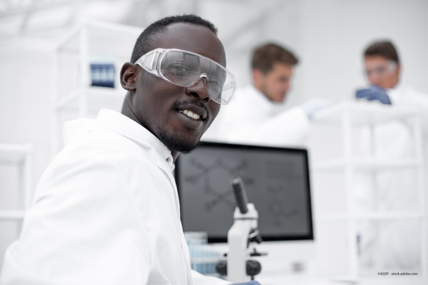 Postdoc smiling for camera with microscope in background