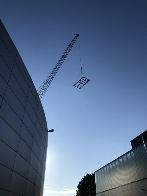 Aufw&auml;rm&uuml;bung: zun&auml;chst wird das Gestell auf dem sp&auml;ter der K&uuml;hlturm stehen wird auf das Dach gehoben. Es ist Donnerstag vor neun Uhr, der Himmel ist blau, die Sonne strahlt!