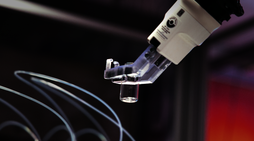 Ein Roboterarm bewegt einen leeren Probenbeh&auml;lter pr&auml;zise zwischen automatisierten Arbeitsstationen hin und her.