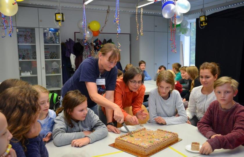 <strong>Happy Birthday, Sch&uuml;lerlabor!</strong> Dr. Ulrike Witte und Dr. Gabriele Lampert (v.l.n.r, beide HZB-Sch&uuml;lerlabor) schneiden die Geburtstagstorte an. Es gibt Gl&uuml;ckw&uuml;nsche und viel Applaus f&uuml;r die Arbeit des Sch&uuml;lerlabors.