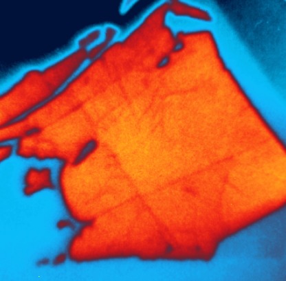 Die Probe besteht aus einer Lage Wolframselenid (orange), die auf einer Schicht aus Molybdänsulfid (blau) aufgebracht ist. Untersuchungen  mit dem SPEEM-Mikroskop an BESSY II zeigen, dass durch Ladungstransfer zwischen den beiden Halbleiterschichten ein elektrisches Potential von bis zu 400meV besteht. 