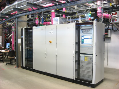 One of the new solid state transmitters: the power supplies are located in the left rack (black), the RF section is located behind the grey doors in the middle and in the right rack the control units can be seen.